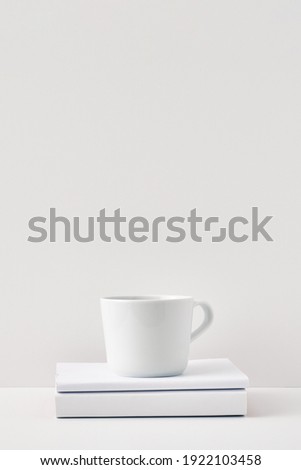 The mug stands on a stack of books on a white background. Natural and eco-friendly materials. Copy space, mock up.
