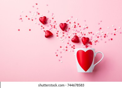 Mug with sugar and chocolate hearts on pink background. Flat lay composition. Romantic, St Valentines Day concept.