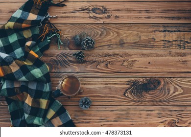 Mug With Tea Bag And Plaid Winter Scarf On Old Brown Wooden Table, Top View