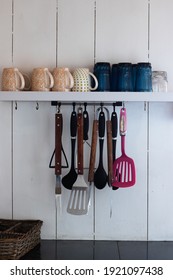Mugs and kitchen tools hang on a hook in a retro kitchen
