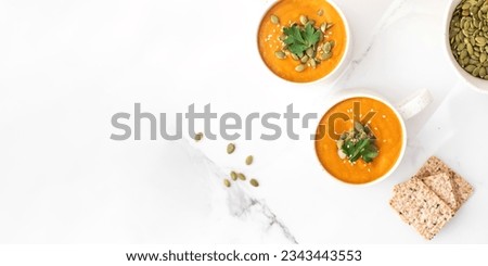 Mugs of warm pumpkin soup. The concept of the autumn menu. Autumn recipes. Copy space