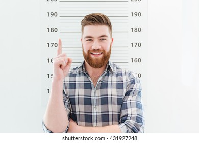 Mugshot Of A Smiling Man Pointing Finger Up