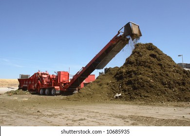 A Mulching Machine Dumps Into A Pile Of Mulch