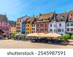 Mulhouse cityscape, typical houses colorful buildings and street restaurant outdoor café on Place de la Reunion square in old town Mulhouse city historic centre, Alsace Grand Est region, France