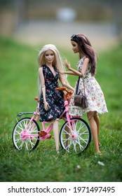 Mulhouse - France - 10 May 2021 - Portrait of two barbie dolls wearing summer dresses and leather handbags  on pink bicycle in a public garden