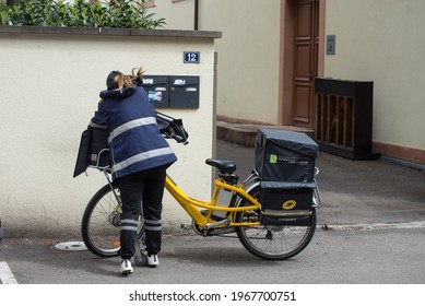 Mulhouse - France - 4 May 2021 - Portrait Of Postwoman Putting Letters In Mail Boxes In The Street