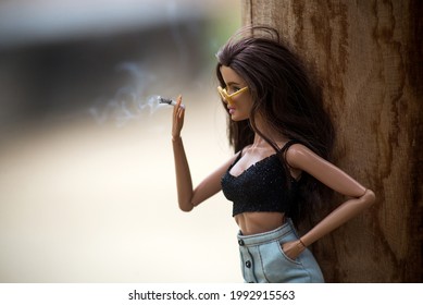 Mulhouse - France - 9 June 2021 - Portrait of brunette barbie doll wearing a mini blue jeans skirt and sexy grey top with a cigarette in hand  in the street