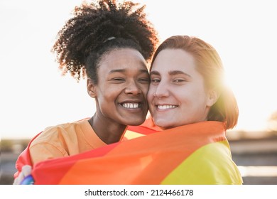 Mulitracial lesbian couple hugging together outdoor with sunset in background - LGBTQIA concept