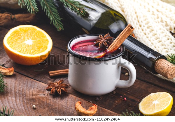 Mulled wine, a bottle of red\
wine, spruce branches, cinnamon, anise tree, orange and lemon on a\
wooden background. A cozy, winter evening. Winter drinks. Christmas\
Eve