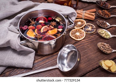 Mulled Wine In A Pot With Handles And Ingredients For Making A Home Made Alcoholic Drink On A Brown Wooden Background, Close Up