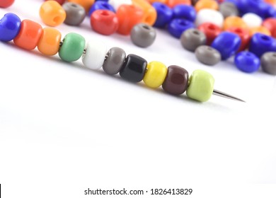 Multi colored Beads spread on white background with needle. Beads with needle . Close up, macro,finishing fashion clothes. make bead necklace, beads for women of fashion,Bead Crochet. Daily Beading.