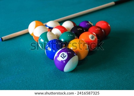 Multi colored billiard balls in the form of a triangle with numbers and cue ball on a pool table. Billiard balls on green table.