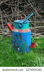 Multi -colored decorative can of jug of a banner in the garden on the grass against the background of trimmed branches blue red colorful - Shutterstock ID 2276901365