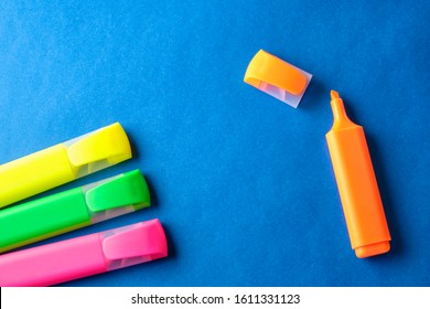 Multi colored highlighters at blue background with copy space
