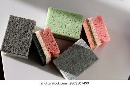 Multi colored kitchen cleaning sponges. Assorted rectangular abrasive foam scrubbers for dishwashing and household maintenance on white surface for cleanliness hygiene and housekeeping concept