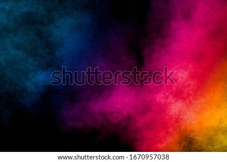 Multi colored particles explosion on black background.Colorful dust splash on dark background.