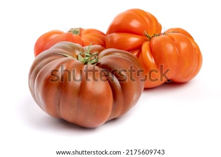 Multi colored red heirloom tomatoes with distinctive wrinkles and creases and irregular shape isolated on white