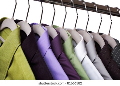 Multi Colored Shirts On Hangers Against A White Background