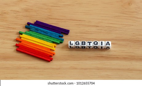 Multi colored stick  and LGBTQIA cube on the wood background. - Shutterstock ID 1012655704