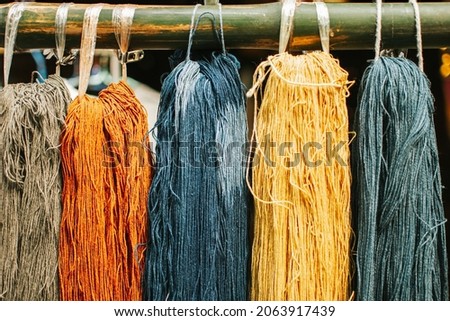 Multi colored threads hanging on bamboo. Hanging skeins of yarn background.