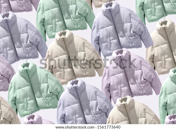 Multi colored women fashion down jacket pattern. A\
selection of different jackets on hangers isolated on beige\
background. Winter clothes pattern. Composition of clothes. Flat\
lay. Padded coat