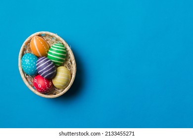 Multi colors Easter eggs in the woven basket on colored background . Pastel color Easter eggs. holiday concept with copy space.