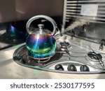 A multi coloured kettle boils on a gas hob with steam visible from spout in a motorhome recreational vehicle.