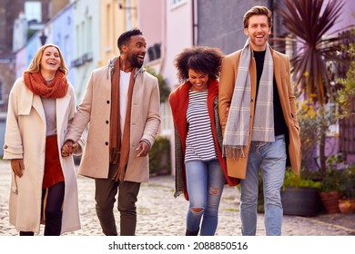 Multi Cultural Couple With Friends Walking Along Residential City Street In Fall Or Winter