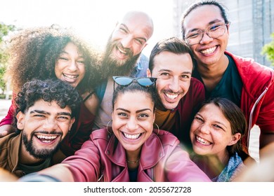 Multi cultural guys and girls taking selfie outdoors with backlight - Happy milenial friendship concept on young multiracial friends having fun day together - Bright vivid filter with sunshine flare
