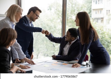 Multi ethnic businessmen project leaders fists bump celebrating corporate achievements, workmates meet in office boardroom surrounded by happy workmates. Reach common decision, share advance concept - Powered by Shutterstock