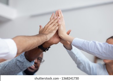 Multi ethnic corporate office business team winners join hands give high five together, success gesture, startup triumph, professional victory, teamwork accomplishment teambuilding concept, close up - Shutterstock ID 1368241730