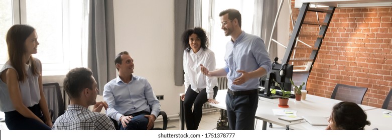 Multi Ethnic Corporate Staff Listen Team Leader Company Boss During Morning Briefing In Coworking Open Space Office. Mentoring, Brainstorming Concept. Horizontal Photo Banner For Website Header Design