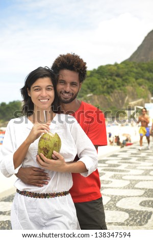 Multi ethnic couple of boyfriends friends tourists drinking coconut water on the edge of Rio de Janeiro.