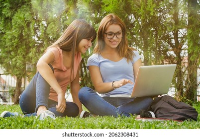 Multi ethnic couple of lesbian teenagers lying on the grass using laptop. Happiness and lightheartedness concept. - Powered by Shutterstock