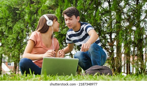 Multi ethnic couple of teenagers lying on the grass using laptop. Happiness and lightheartedness concept. - Powered by Shutterstock