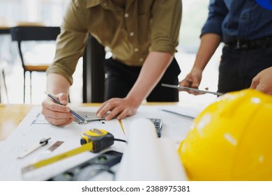 multi ethnic engineer brainstorming and measuring for cost estimating on paperworks and floor plan drawings about design architectural and engineering for houses and buildings.