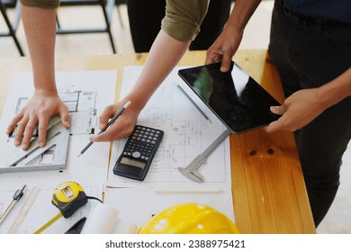 multi ethnic engineer brainstorming and measuring for cost estimating on paperworks and floor plan drawings about design architectural and engineering for houses and buildings.