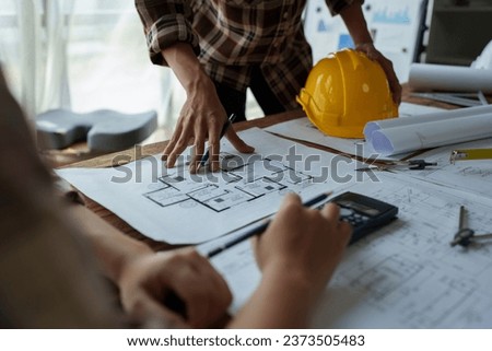 multi ethnic engineer brainstorming and measuring for cost estimating on blueprint and floor plan drawings about design architectural and engineering for houses and buildings.