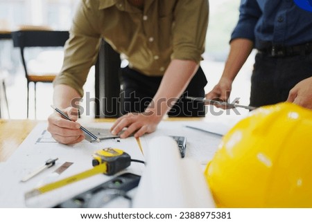 multi ethnic engineer brainstorming and measuring for cost estimating on paperworks and floor plan drawings about design architectural and engineering for houses and buildings.