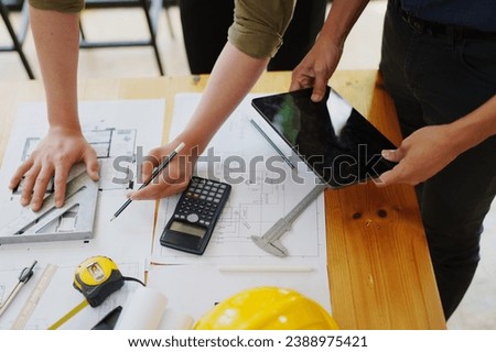 multi ethnic engineer brainstorming and measuring for cost estimating on paperworks and floor plan drawings about design architectural and engineering for houses and buildings.