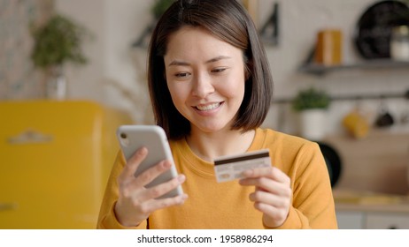 Multi Ethnic Female Client Holding Banking Credit Card And Smart Phone Involved In Verification Process In Mobile Application. Asian Young Woman Doing Payments Online Or Shopping In Internet Store