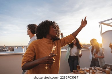 Multi ethnic group of friends hanging out at a rooftop dinner party - Multiracial young people having fun enjoying summer days together - Focus on African woman - - Powered by Shutterstock