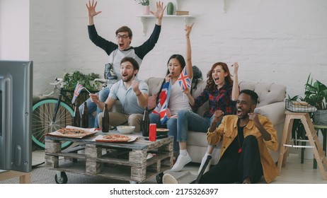 Multi Ethnic Group Of Friends Sports Fans With British National Flags Watching Hockey Championship On TV Together Cheering Up Their Favourite Team At Home Indoors