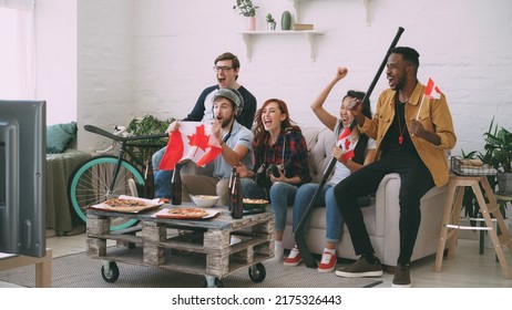 Multi Ethnic Group Of Friends Sports Fans With Canadian National Flags Watching Hockey Championship On TV Together Cheering Up Their Favourite Team At Home Indoors