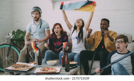 Multi Ethnic Group Of Friends Sports Fans With German National Flags Watching Hockey Championship On TV Together Cheering Up Their Favourite Team At Home Indoors