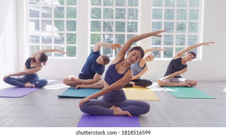 Multi ethnic group of male and female (Asian, Caucasian) join yoga class together in white yoga studio. people stretching on yoga mat - Powered by Shutterstock