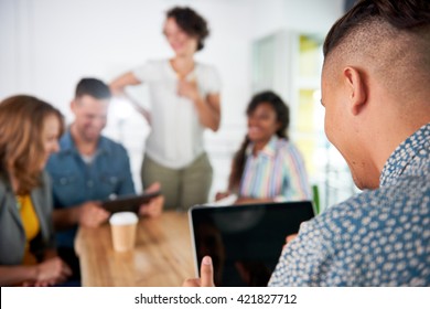 Multi Ethnic Group Of Succesful Creative Business People Using A Laptop During Candid Meeting