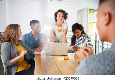 Multi Ethnic Group Of Succesful Creative Business People Using A Laptop During Candid Meeting