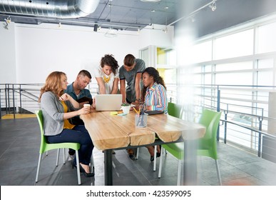 Multi Ethnic Group Of Succesful Creative Business People Using A Laptop During Candid Meeting