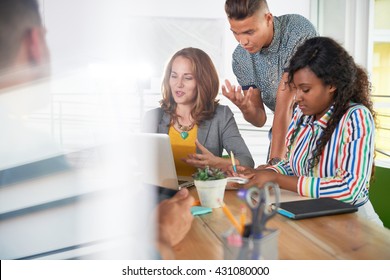 Multi Ethnic Group Of Succesful Creative Business People Using A Laptop During Candid Meeting